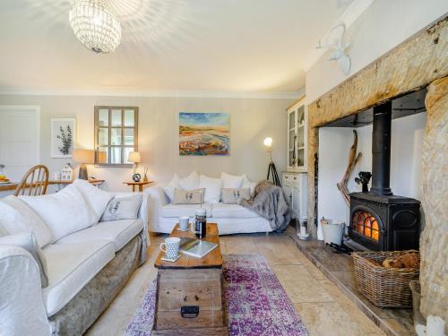 a living room with a white couch and a fireplace at Percy Cottage in Chatton