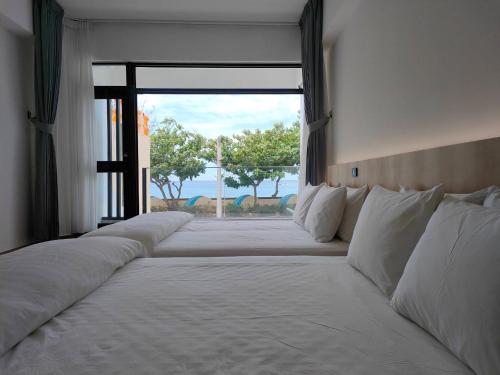 a row of white beds in a room with a window at Kenting Onehome in Checheng