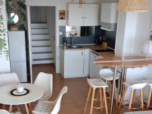 a kitchen with white cabinets and a table and chairs at L'Océan&Dunes vue à 180° en bord de plage in Lacanau-Océan