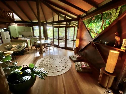 a living room with wooden floors and a dining room at Currumbin Rainforest Treehouse in Currumbin Valley