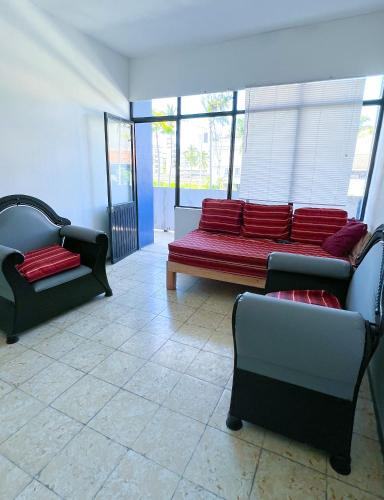 a room with a red bench and two chairs at Vive Alegria Hostel in Puerto Vallarta