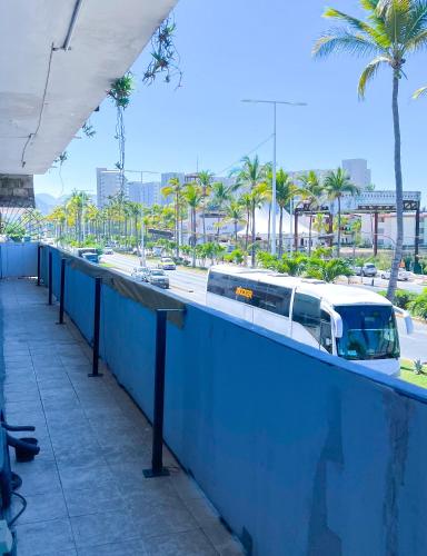 a bus is parked next to a street with palm trees at Vive Alegria Hostel in Puerto Vallarta