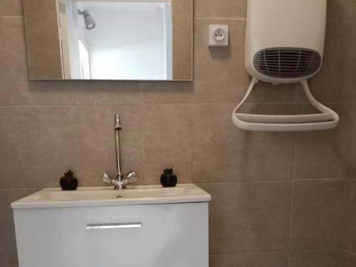 W łazience znajduje się biała umywalka i lustro. w obiekcie L'Océan&Dunes vue à 180° en bord de plage w mieście Lacanau-Océan