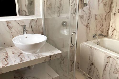 a white bathroom with a sink and a shower at Cómoda casa céntrica con alberca privada en Cancún in Cancún