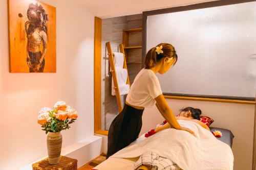 a woman is giving a man a massage at The Hotel Nova in Mandalay