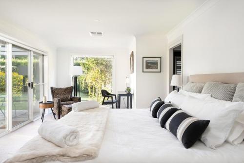 Dormitorio blanco con cama grande con almohadas blancas y negras en Hollydale Burradoo Southern Highlands, en Burradoo
