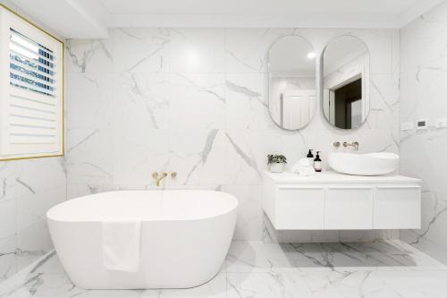 Baño blanco con bañera y lavamanos en Hollydale Burradoo Southern Highlands, en Burradoo