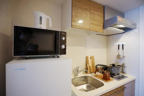 a microwave on top of a refrigerator in a kitchen at 川HOUSE黒門 in Osaka
