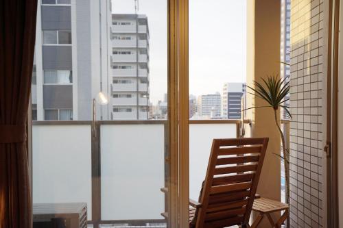 a wooden chair sitting in front of a window at 川HOUSE黒門 in Osaka
