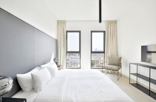 a bedroom with a large white bed with windows at Madinat Jumeirah Living, MJL Dubai in Dubai