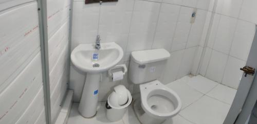 La petite salle de bains est pourvue de toilettes et d'un lavabo. dans l'établissement Hospedaje Mirador Grecia, à Leticia