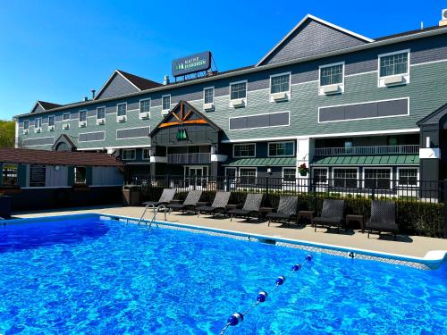 a hotel with a swimming pool in front of a building at Maine Evergreen Hotel, Ascend Hotel Collection in Augusta