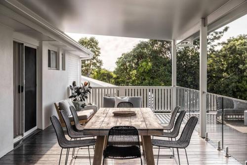 een veranda met een houten tafel en stoelen op een terras bij The Aura House in Tweed Heads
