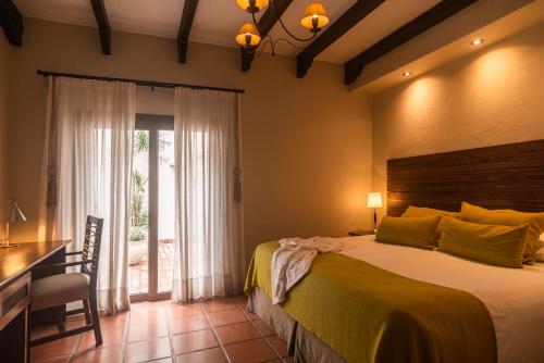 a bedroom with a bed and a desk and a window at Hotel Boutique Balcón de la Plaza in Salta