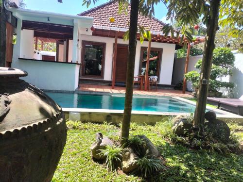 a villa with a swimming pool in front of a house at Baruna Sari Villa in Ubud