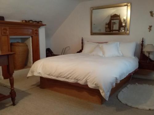 1 dormitorio con 1 cama con sábanas blancas y espejo en Josie's Cottage en Hobart
