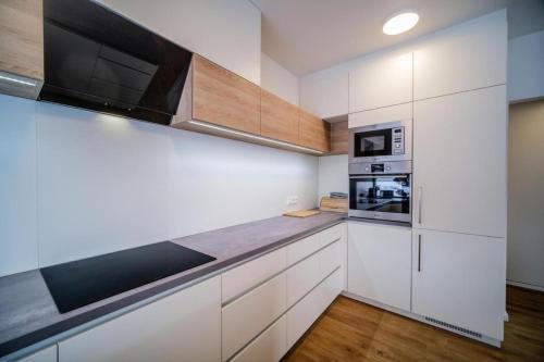 a kitchen with white cabinets and a microwave at Chata Lipno U Hajenky in Lipno nad Vltavou