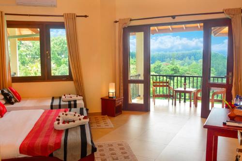 a bedroom with two beds and a balcony with a view at The Grand Hills in Kandy