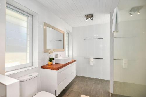 La salle de bains blanche est pourvue de toilettes et d'un lavabo. dans l'établissement Diamond Head Manor, à Budgewoi