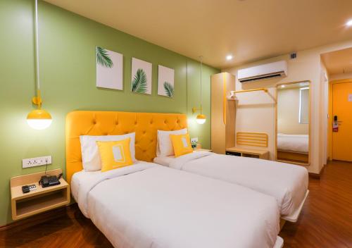 a hotel room with two beds with yellow and green walls at Bloom Hotel - Golf Course Road, Sector 43 in Gurgaon