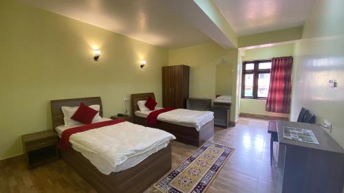 a hotel room with two beds and a table and a desk at Lingmoo Residency in Ravangla