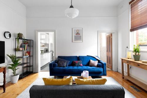 a living room with a blue couch and a table at Iconic Lygon street Home, Carlton in Melbourne