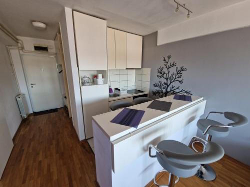 uma cozinha com um balcão branco e uma cadeira em Harmony Apartment em Belgrado