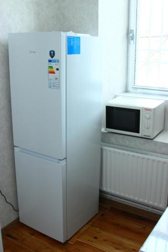 a white refrigerator in a kitchen with a microwave at Guest house 17/7 in Gyumri