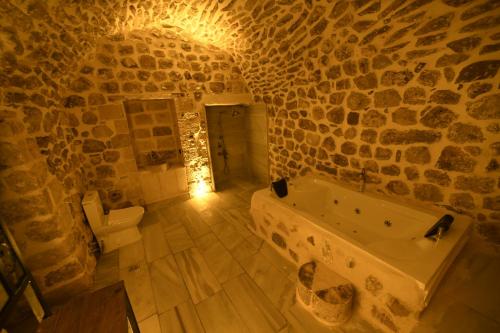 a stone bathroom with a tub and a toilet at Legacy Mesopotamia Hotel in Mardin