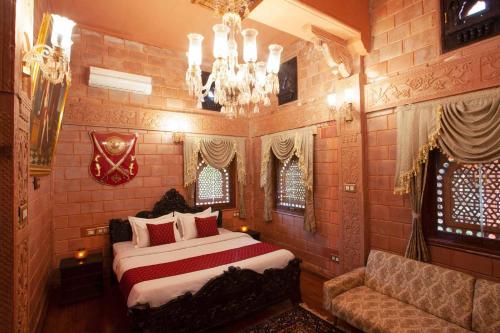 ein Schlafzimmer mit einem Bett, einer Couch und einem Kronleuchter in der Unterkunft StayVista at Pink Palace Rajasthani Decor in Udagamandalam