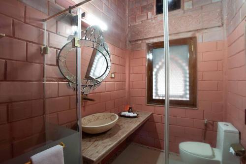 ein rosafarbenes Bad mit einem Waschbecken und einem Spiegel in der Unterkunft StayVista at Pink Palace Rajasthani Decor in Udagamandalam