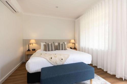 a bedroom with a large white bed with a blue bench at Clare Country Club in Clare