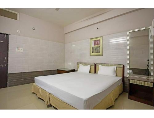 a bedroom with a large white bed and a sink at Jay Shanti Palace, Dewas in Dewās