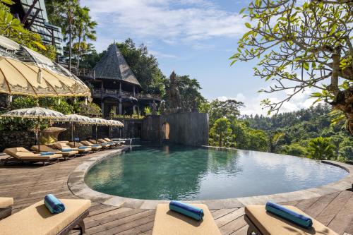 a swimming pool at a resort with lounge chairs at The Kayon Valley Resort in Ubud