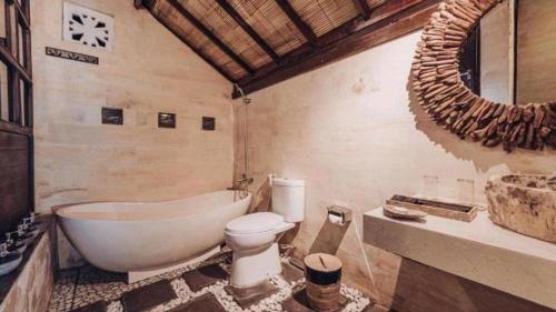 a bathroom with a tub and a toilet and a sink at Kayu Manise Villa Bedugul in Tabanan