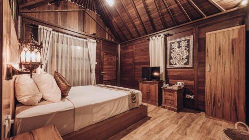 a bedroom with a bed in a room with wooden walls at Kayu Manise Villa Bedugul in Tabanan