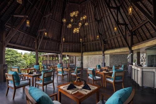 The Kayon Valley Resort في أوبود: مطعم بطاولات وكراسي وثريا