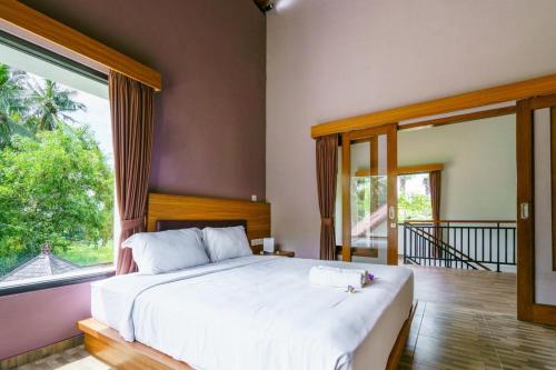 - une chambre avec un grand lit et une grande fenêtre dans l'établissement Ariana Beach Resort Amed Bali, à Amed