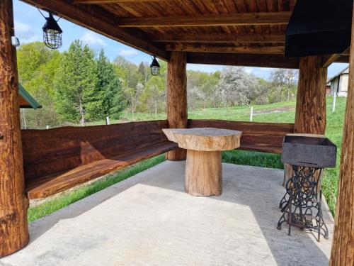 a wooden pavilion with a bench and a grill at Vysoka brama дерев'яний будиночок з чаном in Oriv