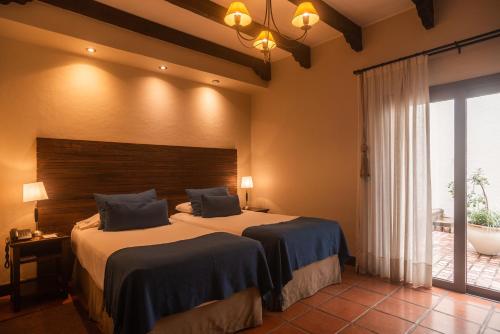 a bedroom with two beds and a large window at Hotel Boutique Balcón de la Plaza in Salta