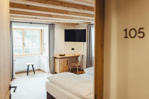 a hotel room with a bed and a desk and a window at Hotel Schmuckhof in Chiusa