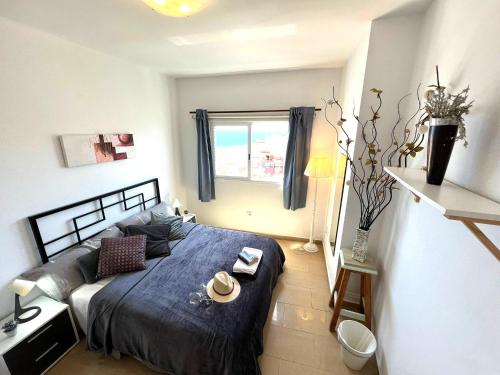 a bedroom with a bed with a blue comforter and a window at ALCAMAR APARTMENT! with beautiful views of the sea! in Alcalá