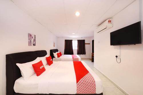 una camera da letto con un grande letto bianco con cuscini rossi di OYO 1132 Azimaju Guesthouse a Malacca