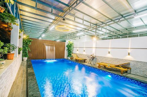 a large indoor pool with blue water in a building at Maldives Hotel - FLC Sầm Sơn in Sầm Sơn