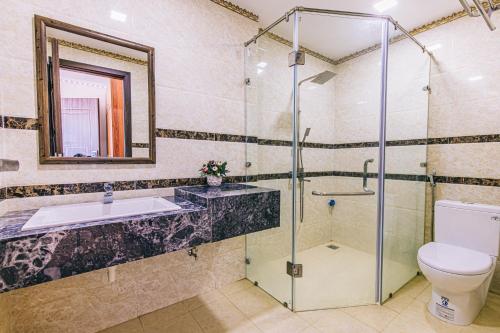 een badkamer met een douche, een wastafel en een toilet bij Maldives Hotel - FLC Sầm Sơn in Sầm Sơn