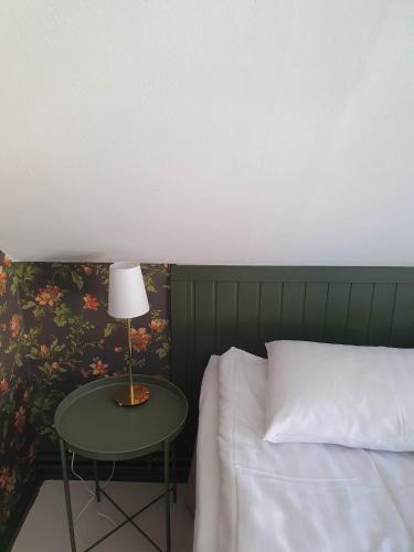 a bedroom with a bed and a table with a lamp at Epokgården in Öregrund