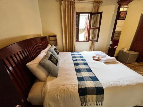a bedroom with a bed with a plaid blanket on it at Khounphet Heritage House in Luang Prabang