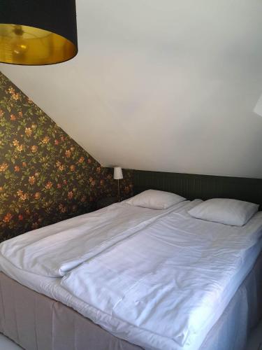 a large white bed in a room with a wall at Epokgården in Öregrund