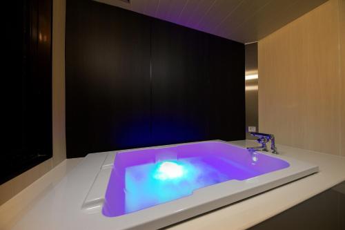 a bathroom with a tub with a purple light in it at Hotel Benkyo Beya Amagasaki in Amagasaki