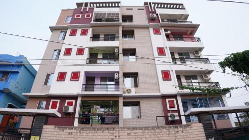 um edifício branco alto com portas e janelas vermelhas em The Royals Home Stay em Deoghar